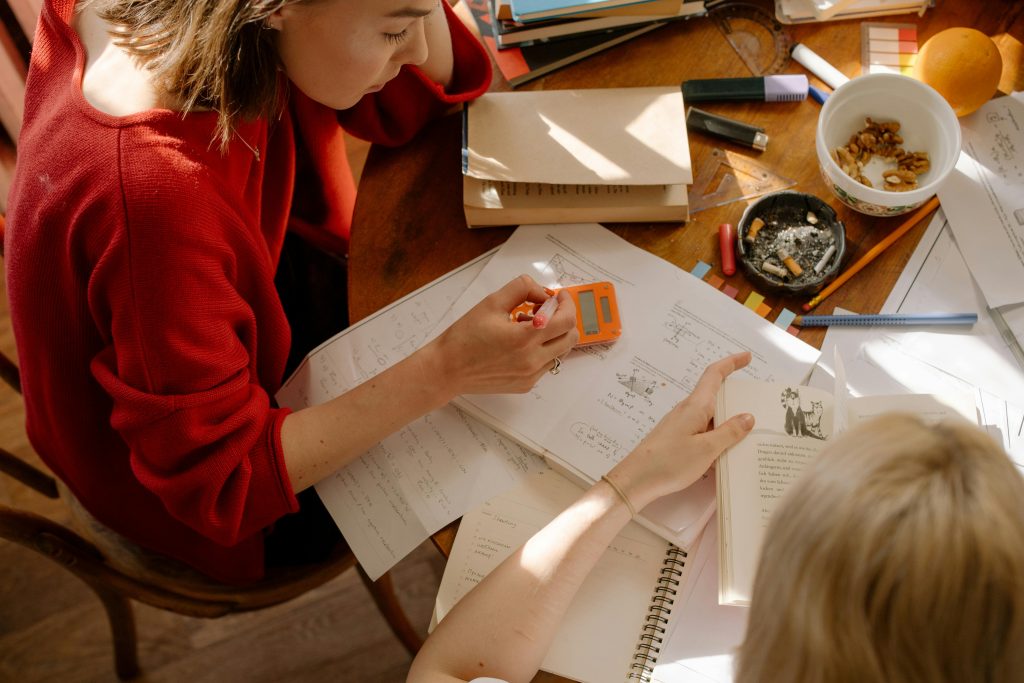 Girl in Red Long Sleeve Shirt Writing on White Paper